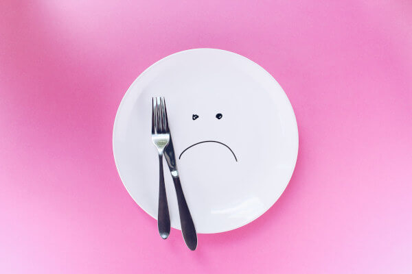 Un plato con cara triste que simboliza la dieta blanca alimentos prohibidos